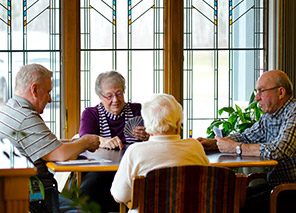 Residents gathered around a table, representing social activities and community connections at Moose Lake Village.